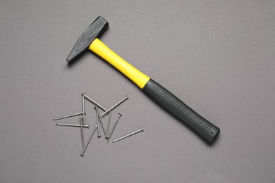 Hammer and metal nails on grey background, top view