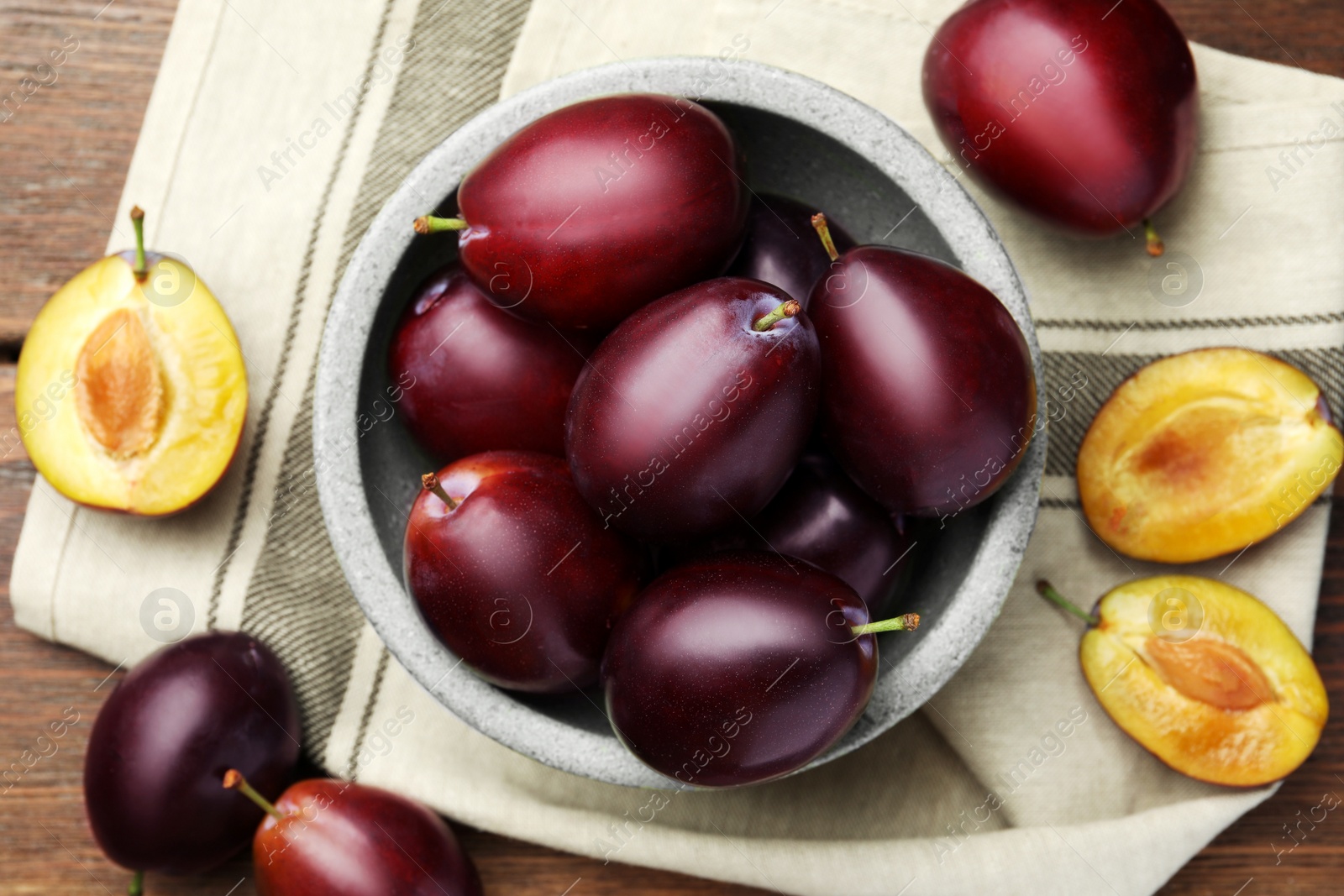 Photo of Tasty ripe plums on wooden table, flat lay