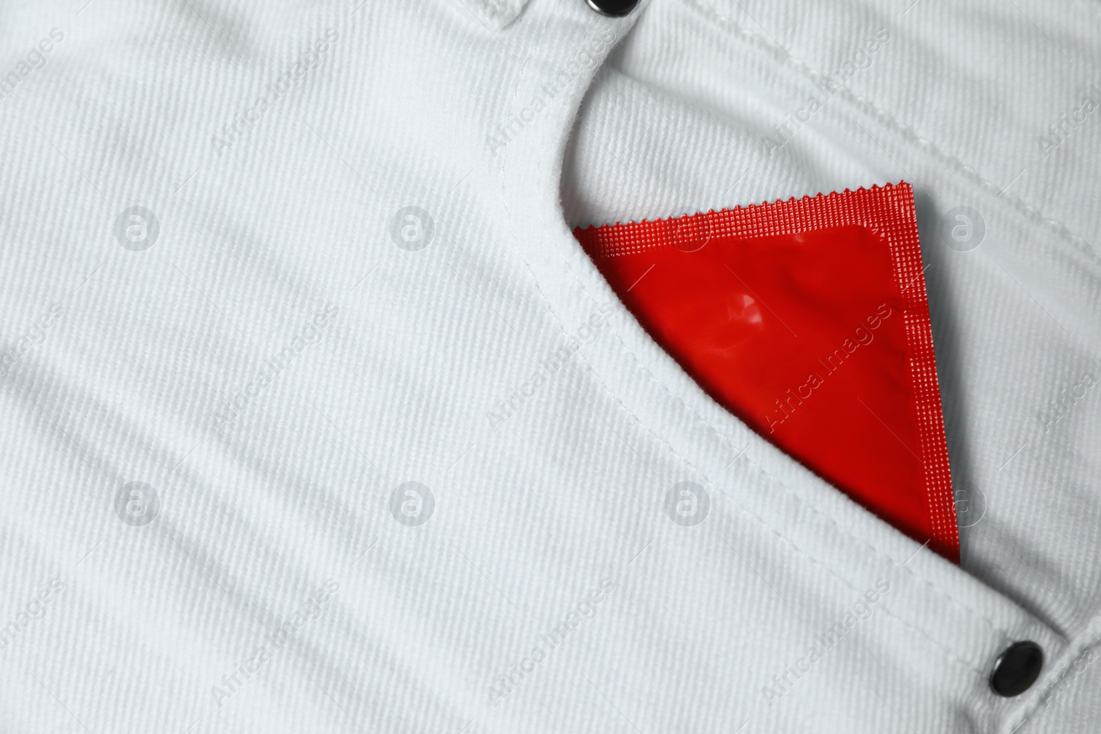 Photo of Packaged condom in white jeans pocket, closeup. Safe sex