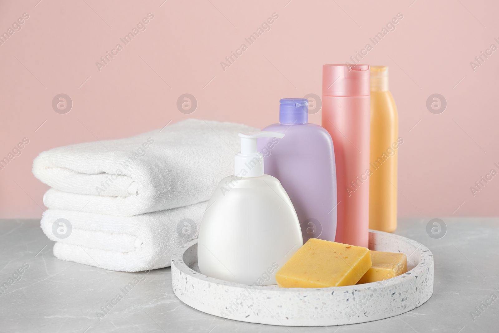 Photo of Fresh towels and toiletries on light grey marble table