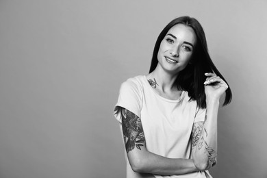 Image of Young woman with tattoos on light background, space for text. Black and white photography