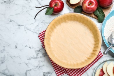 Flat lay composition with raw dough and ingredients on white marble table, space for text. Baking apple pie