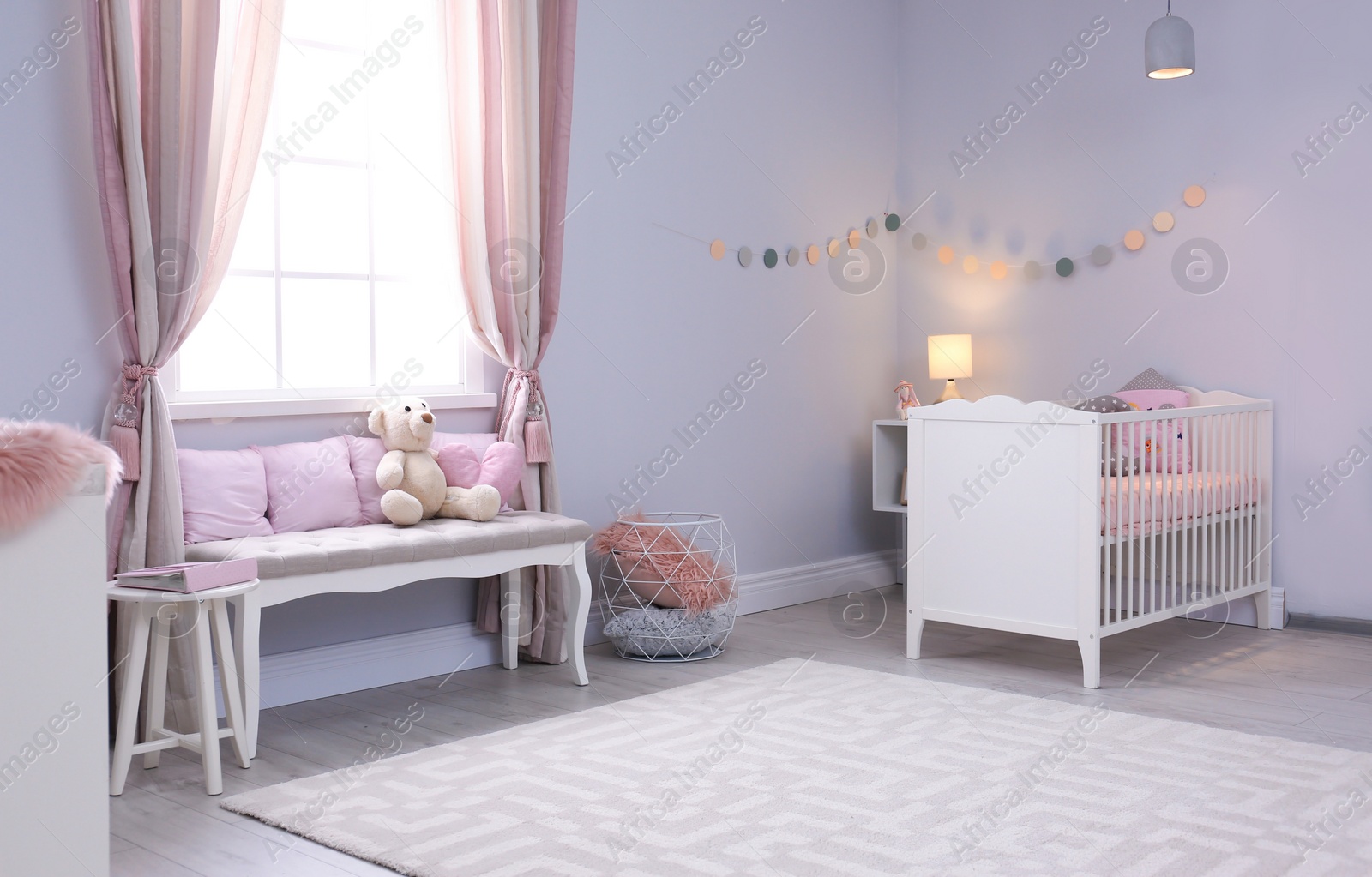 Photo of Baby room interior with comfortable crib and indoor bench