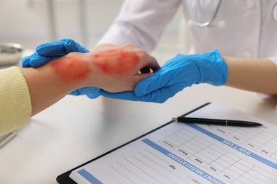 Doctor examining patient's burned hand in hospital, closeup