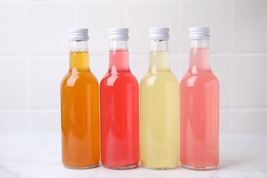 Photo of Delicious kombucha in glass bottles on white marble table