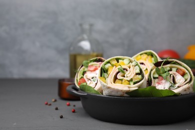 Delicious sandwich wraps with fresh vegetables on grey table, closeup. Space for text
