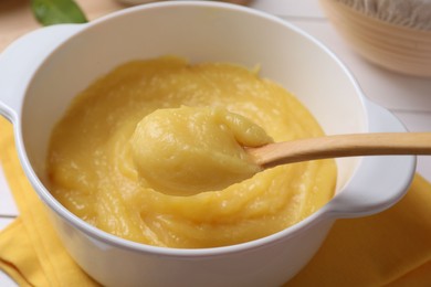 Photo of Taking delicious lemon curd from bowl at table, closeup