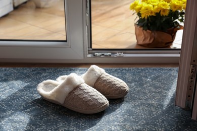 Photo of Pair of beautiful soft slippers on mat in room