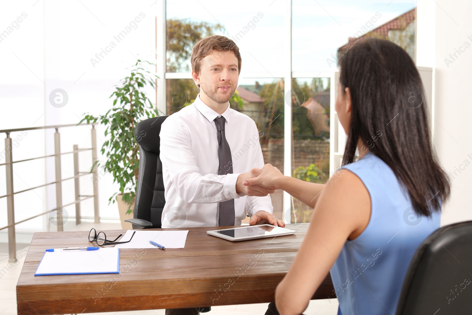 Photo of Human resources manager shaking hands with applicant during job interview in office