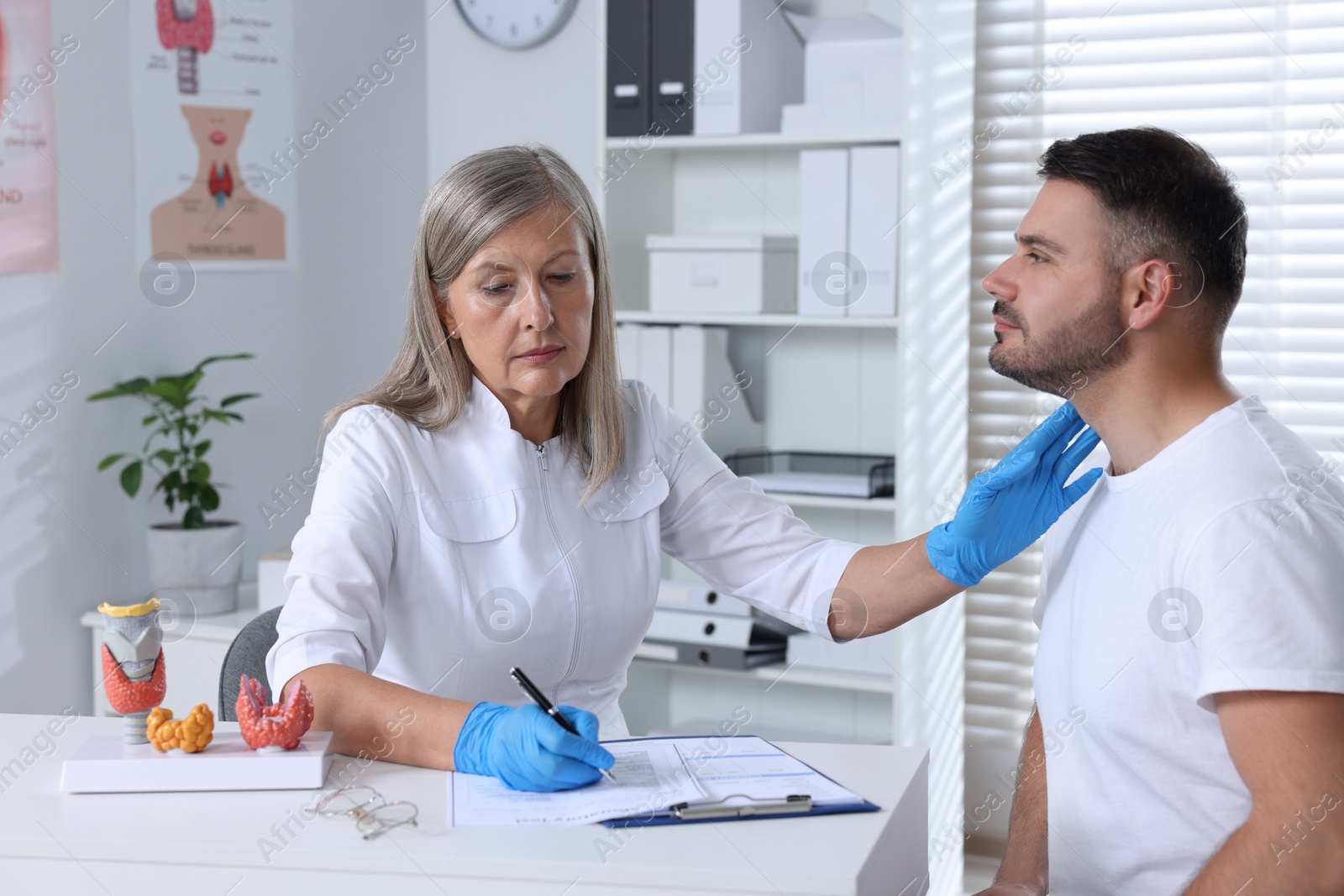 Photo of Endocrinologist examining thyroid gland of patient at table in hospital