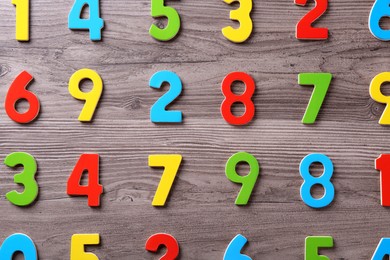 Photo of Colorful numbers on wooden school desk, flat lay