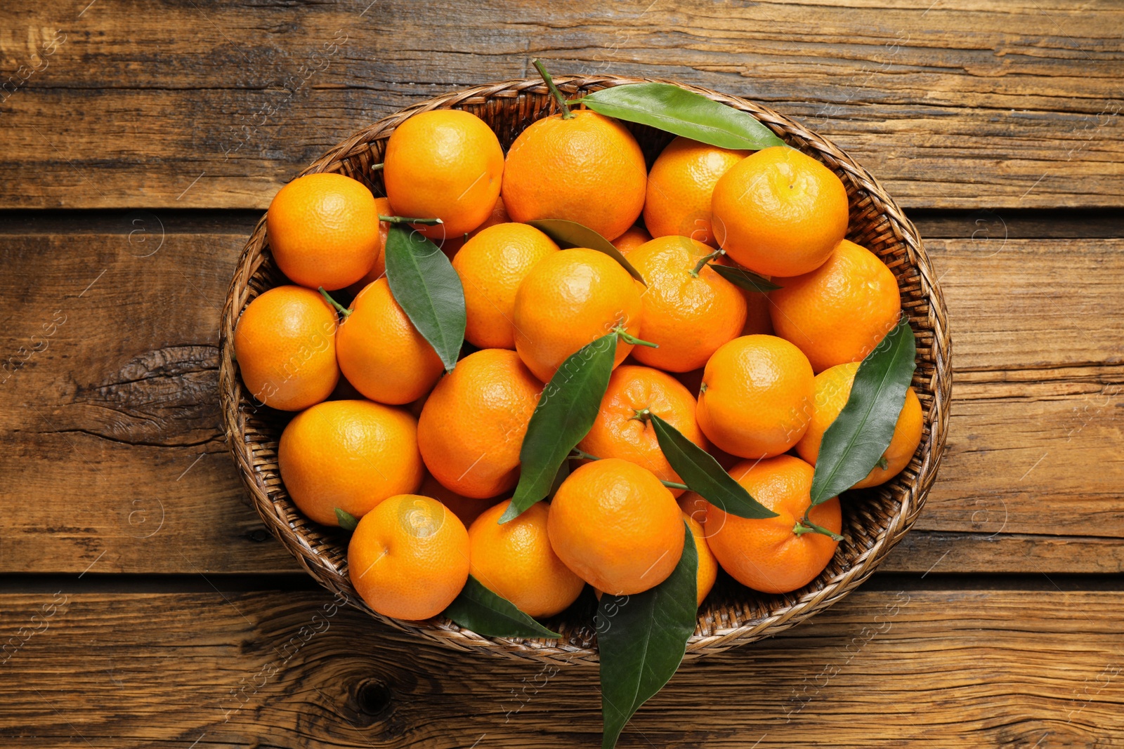 Photo of Fresh ripe tangerines with leaves on wooden table, top view. Citrus fruit