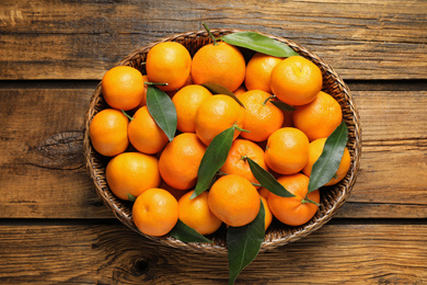 Fresh ripe tangerines with leaves on wooden table, top view. Citrus fruit