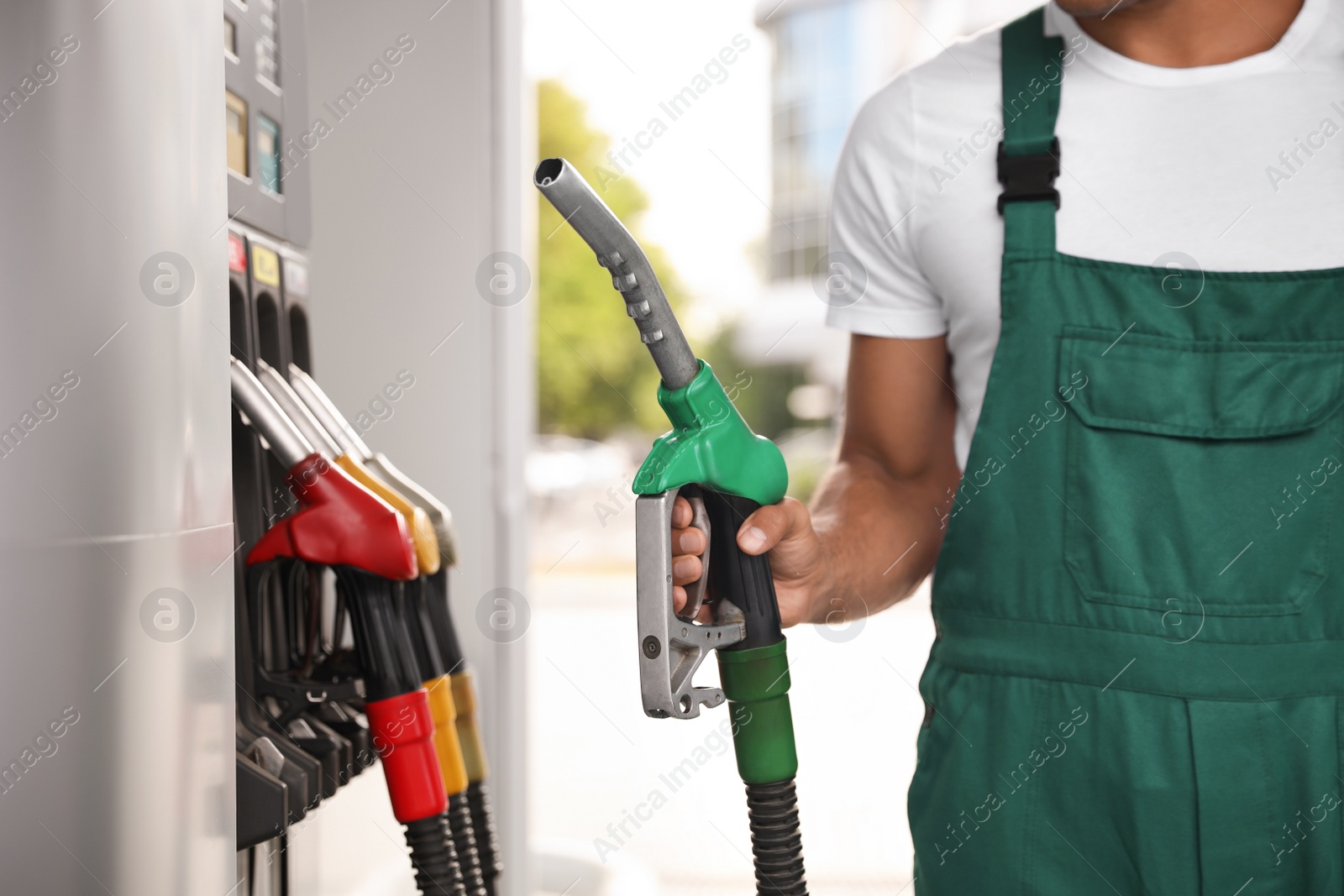 Photo of Worker with fuel pump nozzle at modern gas station, closeup