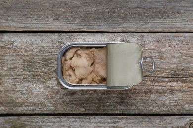Photo of Open tin can of tasty cod liver on wooden table, top view