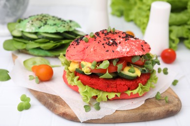 Photo of Tasty pink vegan burger with vegetables, patty and microgreens on white tiled table, closeup. Space for text