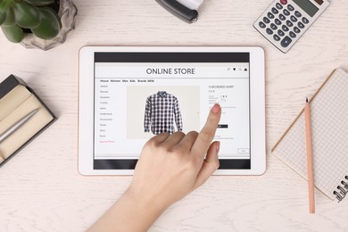 Photo of Woman with tablet shopping online at white wooden table, top view