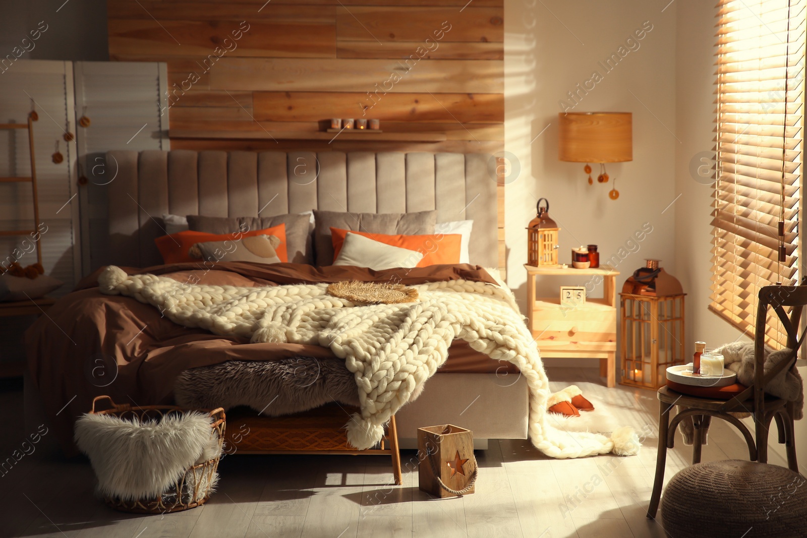 Photo of Cozy bedroom interior with knitted blanket and cushions