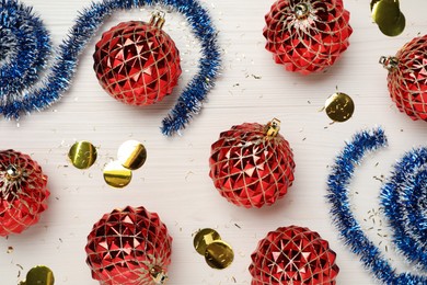 Blue tinsel, confetti and Christmas balls on white wooden background, flat lay