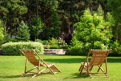 Photo of Wooden deck chairs in beautiful garden on sunny day