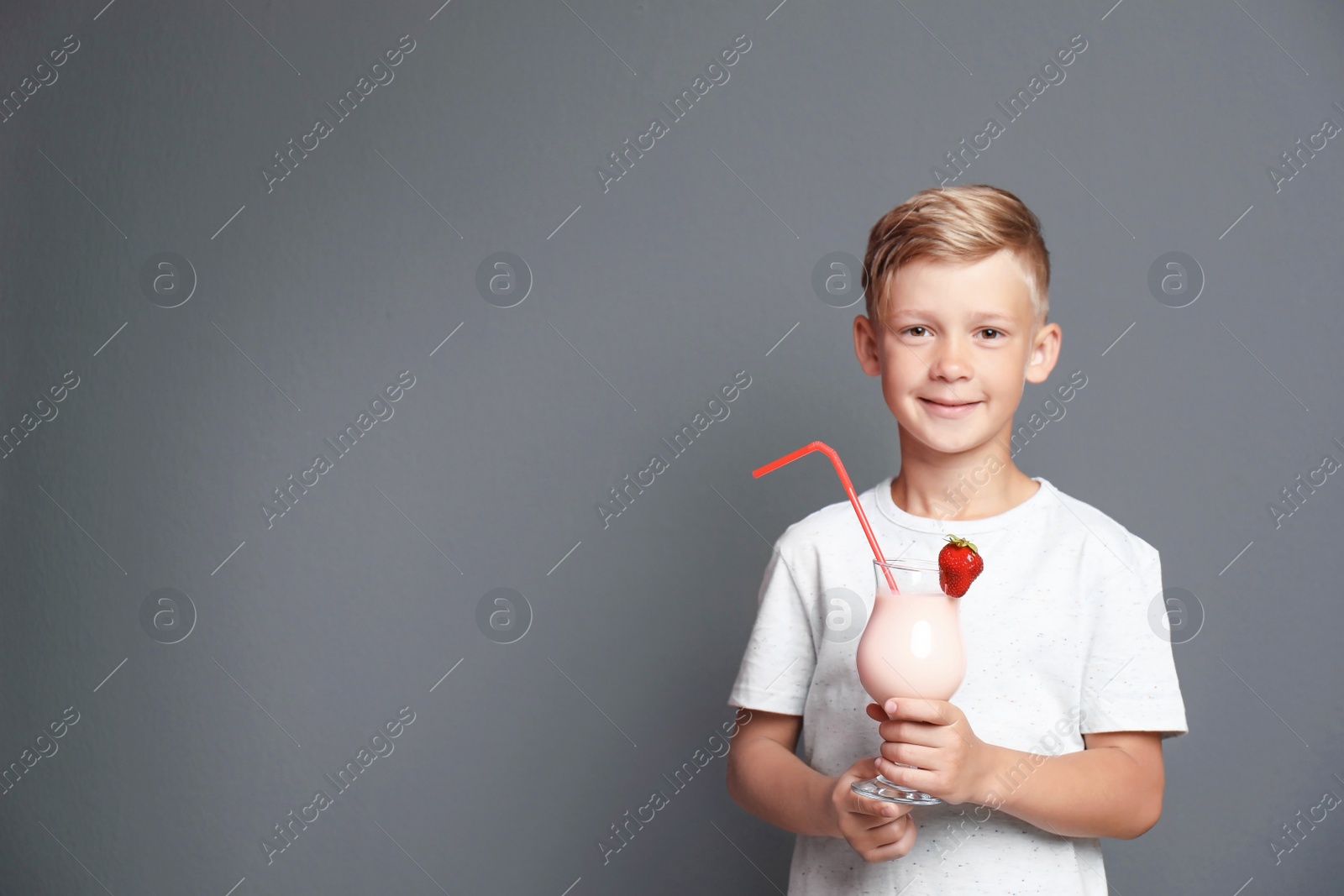 Photo of Little boy with glass of milk shake on grey background