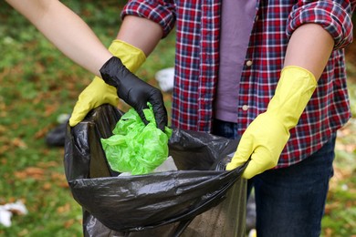 Photo of Man and woman with plastic bag collecting garbage in park, closeup
