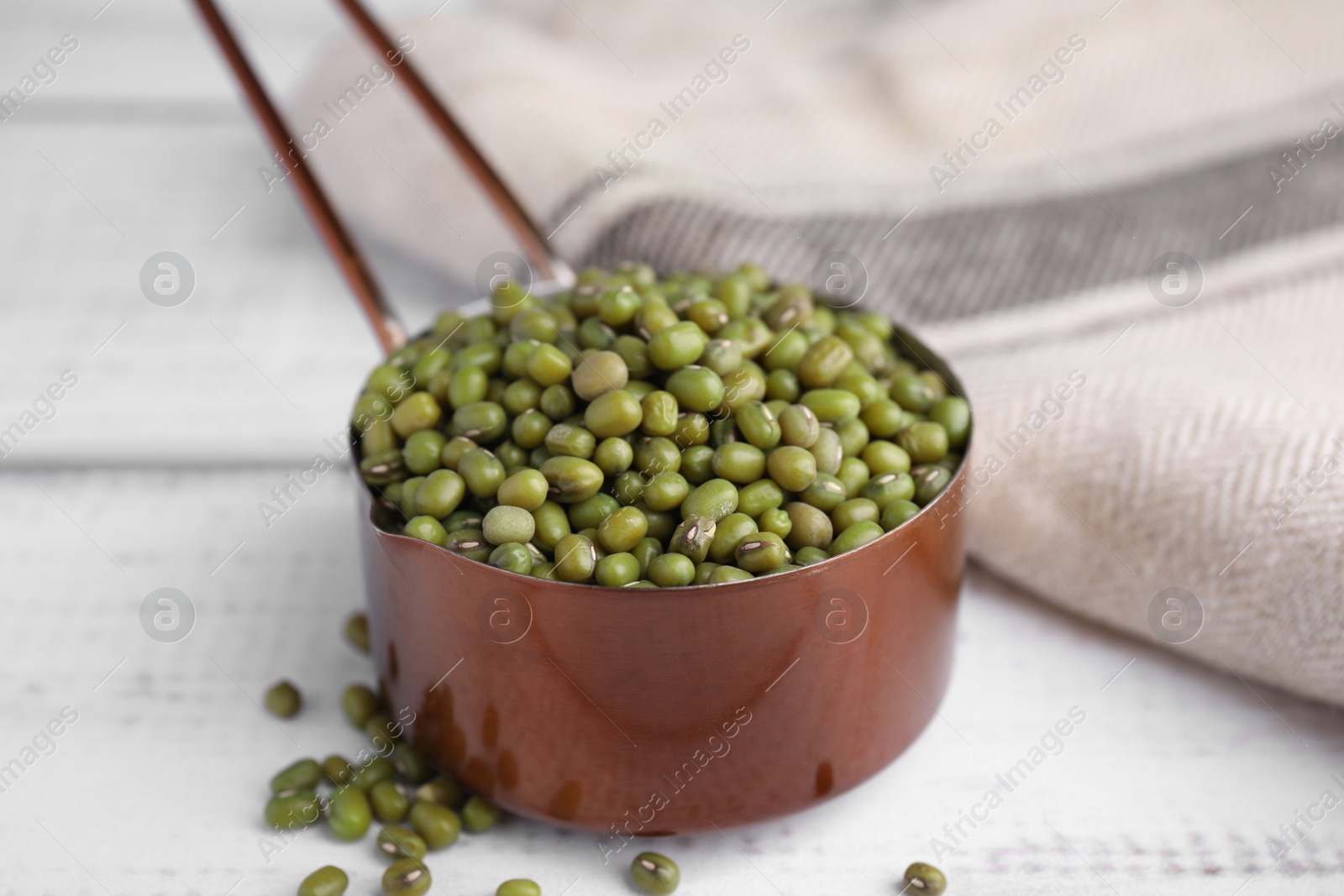 Photo of Scoop with mung beans on white wooden table, closeup