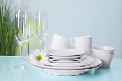 Photo of Set of clean dishware and flower on light blue table