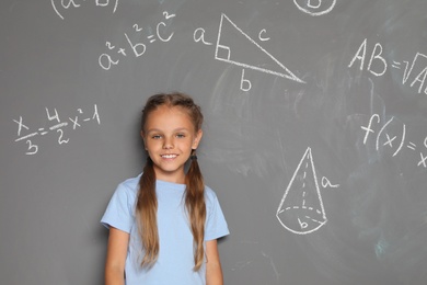 Photo of Little school child and mathematical formulas on grey background