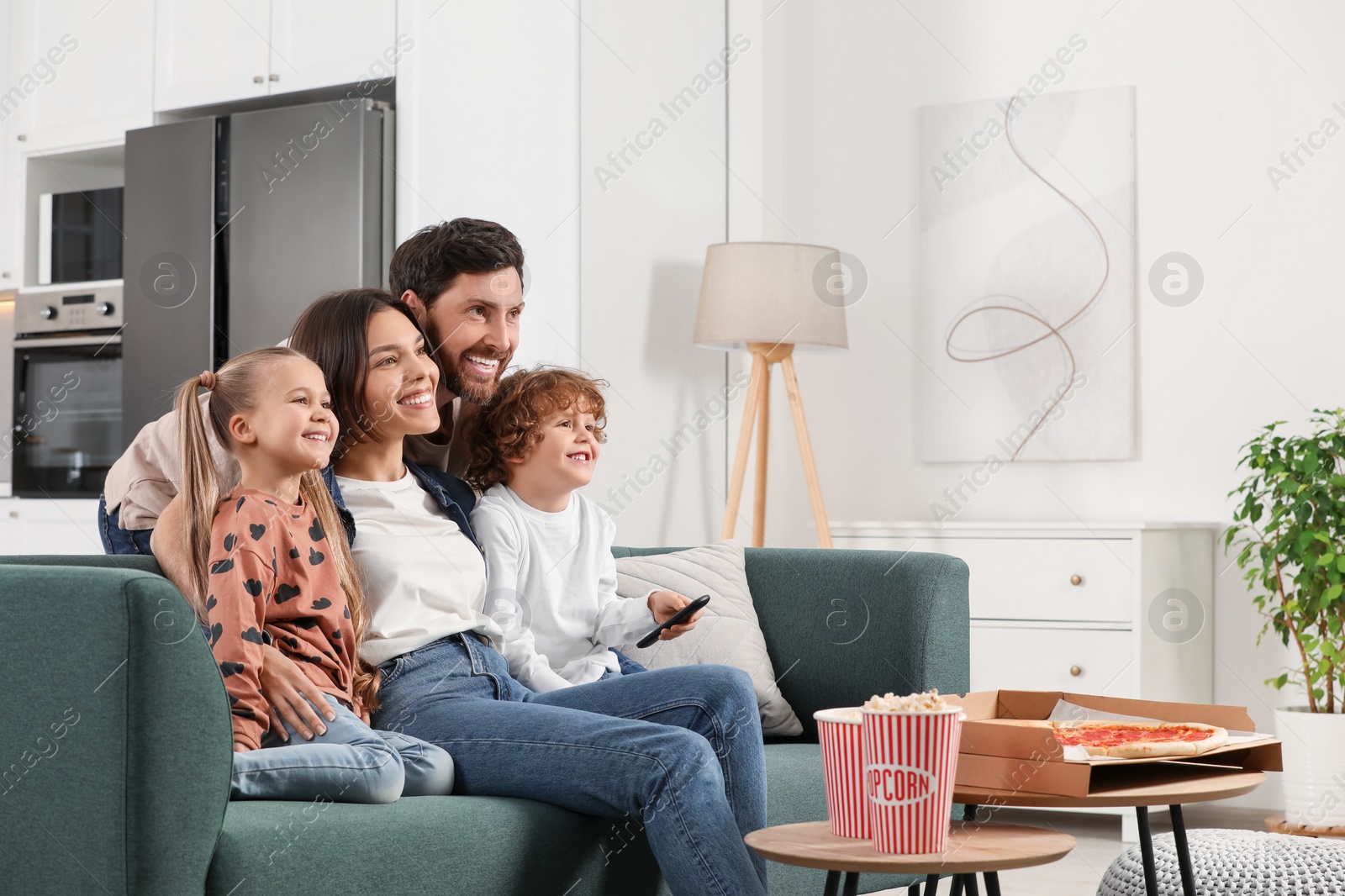 Photo of Happy family watching TV with popcorn and pizza on sofa at home, space for text