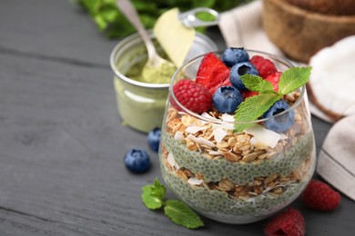 Tasty oatmeal with chia matcha pudding and berries on black wooden table, closeup. Space for text. Healthy breakfast