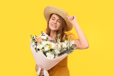 Photo of Happy woman in straw hat with bouquet of beautiful flowers on yellow background