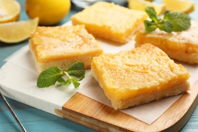 Tasty lemon bars and mint on light blue wooden table, closeup