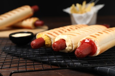 Photo of Delicious french hot dogs and dip sauce on wooden table, closeup