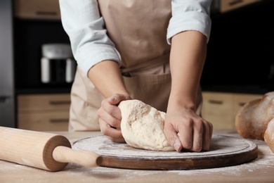 Photo of Female baker preparing bread dough at table, closeup