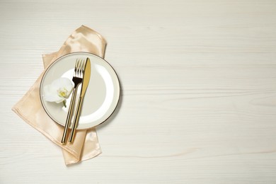 Stylish setting with elegant cutlery on white wooden table, top view. Space for text