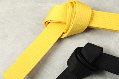 Photo of Black and yellow karate belts on gray marble background, closeup