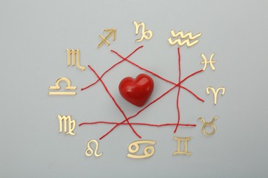 Photo of Zodiac compatibility. Signs, red heart and threads on grey background, flat lay