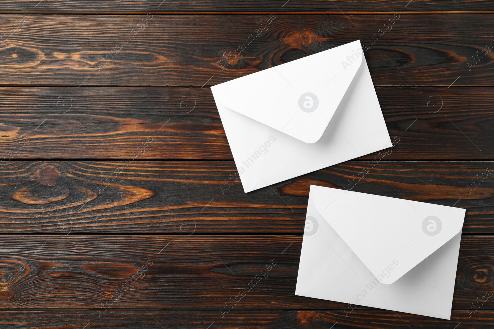 Photo of White paper envelopes on wooden background, flat lay. Space for text