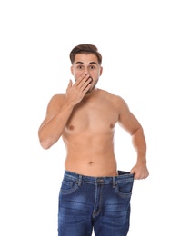 Fit man in oversized jeans on white background. Weight loss