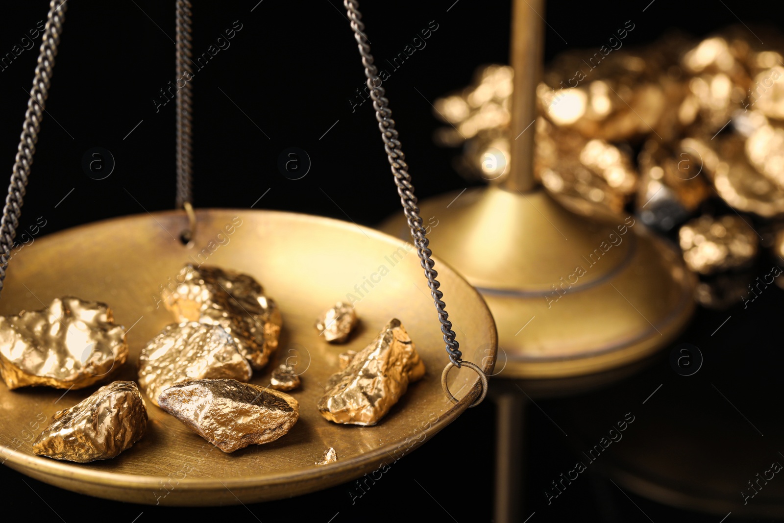 Photo of Vintage scales with gold nuggets on black background, closeup