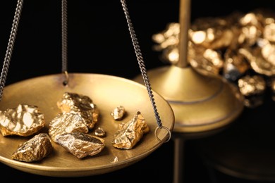 Vintage scales with gold nuggets on black background, closeup