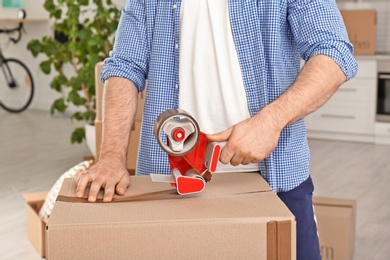 Man packing cardboard box indoors, closeup. Moving day