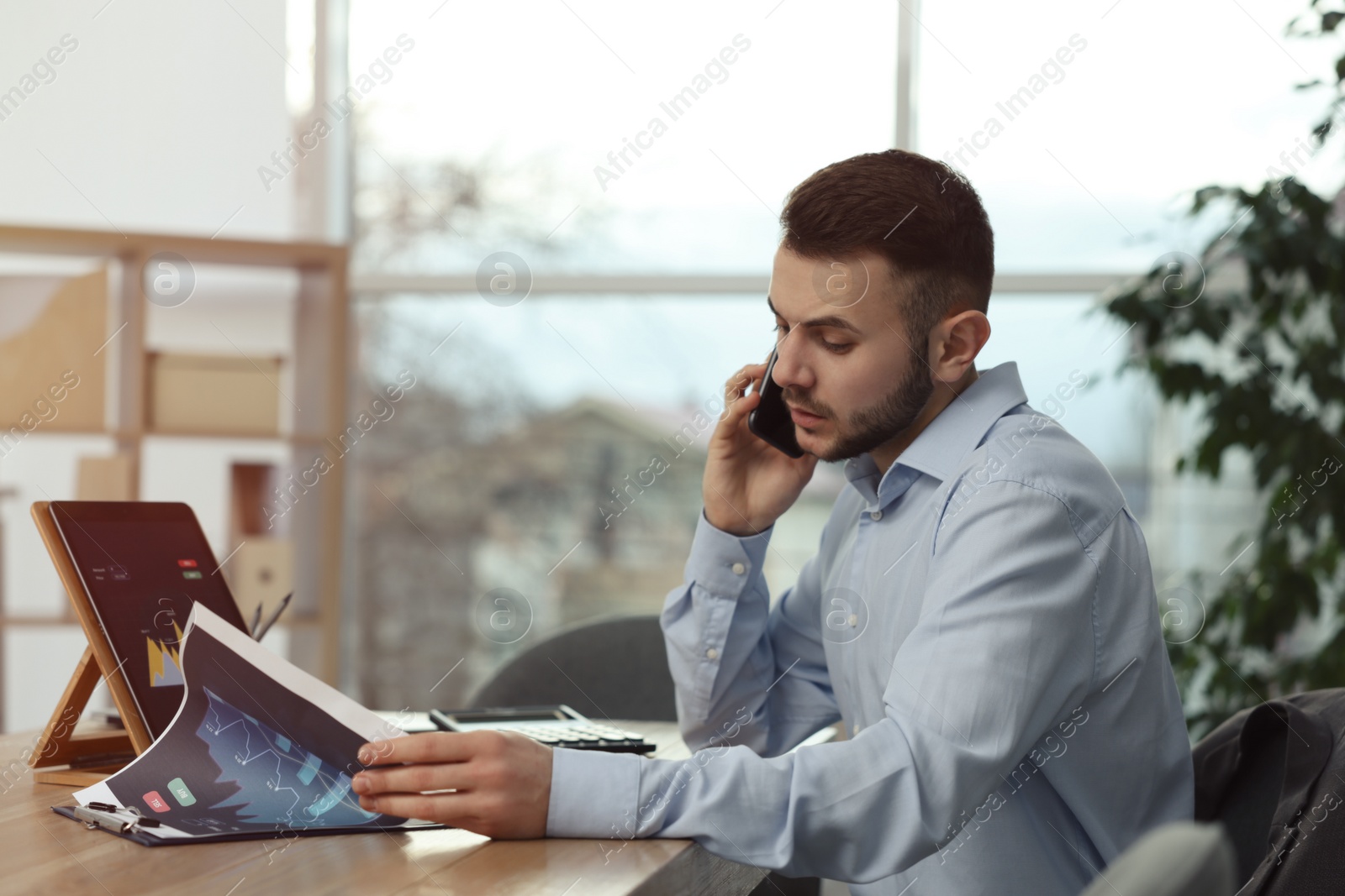 Photo of Forex trader talking on phone while working in office