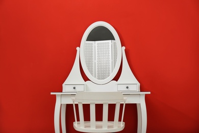 Photo of Elegant white makeup table and chair on red background