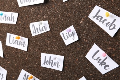 Paper pieces with baby names on cork board, closeup