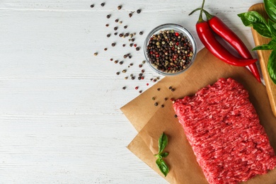 Photo of Flat lay composition with fresh raw minced meat on white wooden table. Space for text