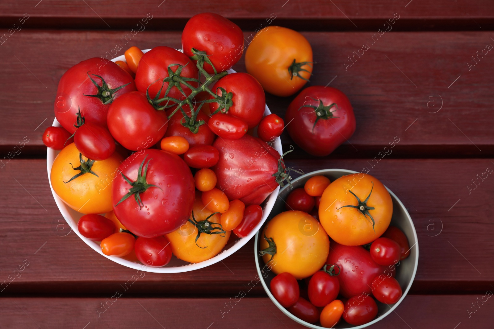 Photo of Bowls with fresh tomatoes on wooden table, flat lay