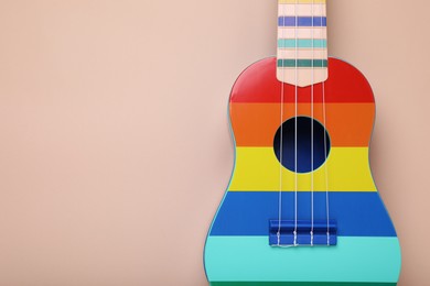 Photo of Colorful ukulele on beige background, top view and space for text. String musical instrument