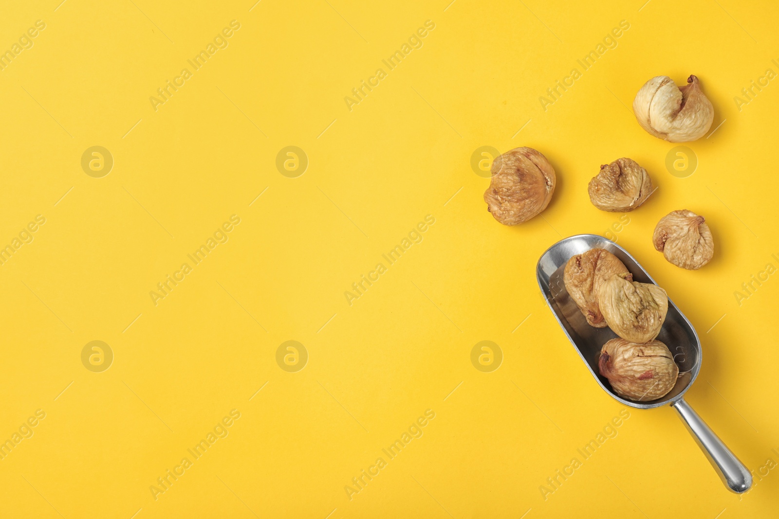 Photo of Scoop of dried figs on color background, top view with space for text. Healthy fruit